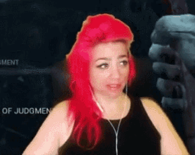 a woman with red hair is wearing a black tank top and earbuds .