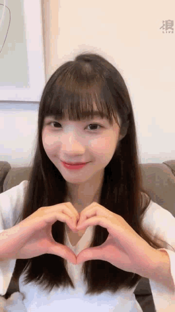 a woman is making a heart shape with her hands .