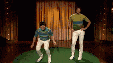 two men in striped shirts and white pants are jumping in the air on a stage