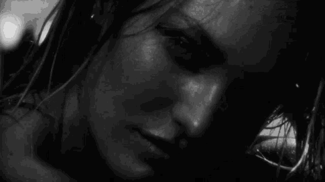 a black and white photo of a woman 's face with wet hair