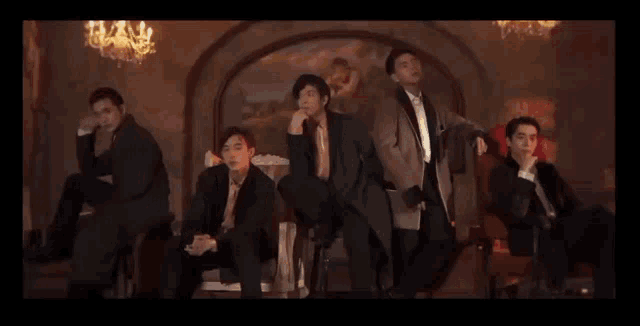 a group of men in suits are sitting in chairs