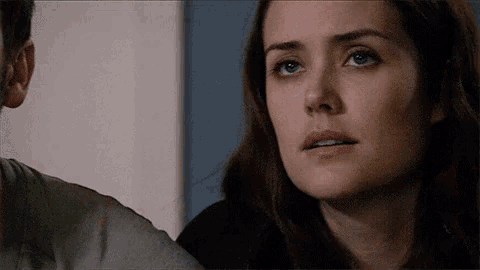 a close up of a woman 's face with a man 's ear in the background
