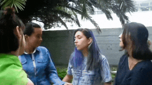 a woman with purple hair is surrounded by three other women
