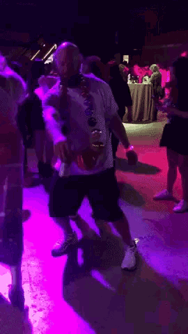 a man wearing a hawaiian lei is dancing in a club
