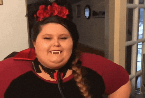 a woman wearing a vampire costume with fangs and a red flower in her hair