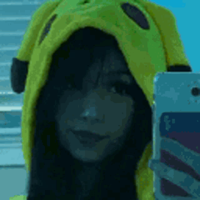 a woman is taking a selfie with her phone while wearing a yellow hoodie .