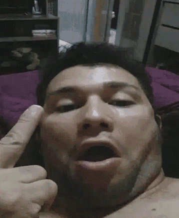 a man without a shirt is making a funny face with his finger on his forehead