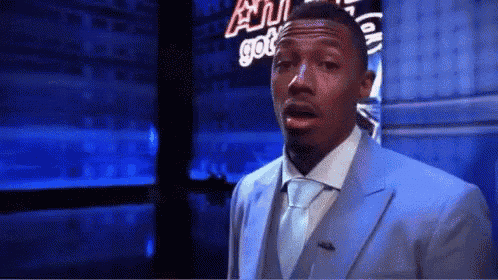 a man in a suit and tie is standing in front of a neon sign that says ' all got ' on it .