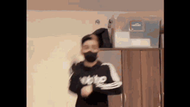 a man wearing a mask is dancing in a room in front of a wardrobe .