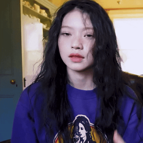 a woman with long black hair is wearing a purple shirt