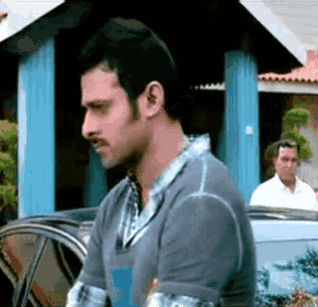 a man with a mustache is standing in front of a building