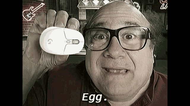 a bald man wearing glasses is holding a computer mouse in his hand and saying `` egg '' .