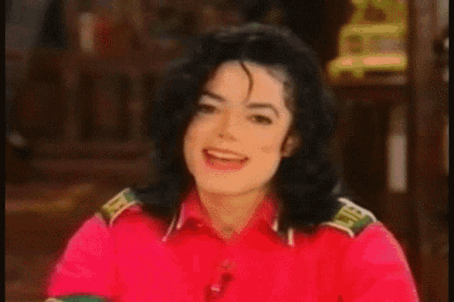 a close up of a man wearing a red shirt smiling