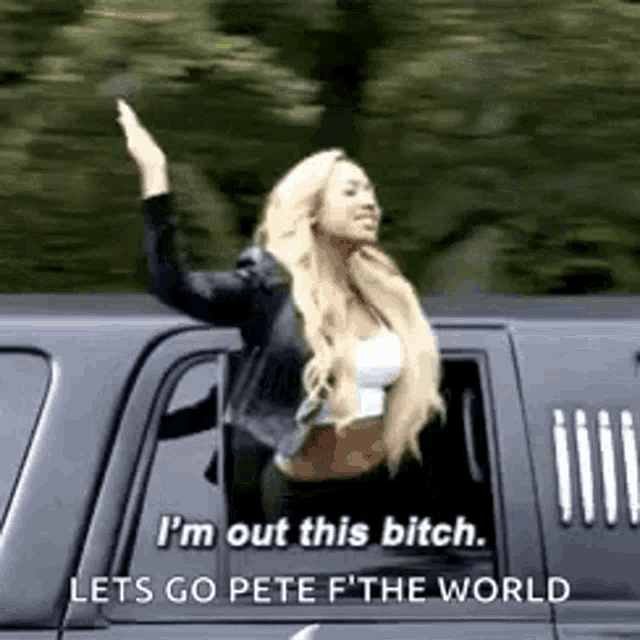 a woman is waving out of a car window while driving .