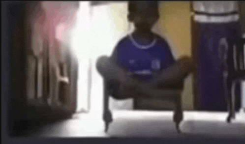 a young boy in a blue shirt is sitting on a chair in a room .