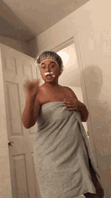 a woman wrapped in a towel with a shower cap on her hair