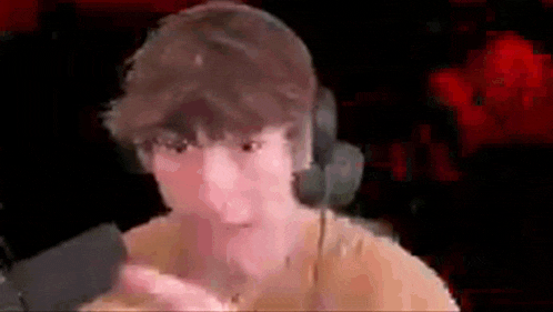 a man wearing headphones and a yellow shirt is making a funny face in front of a microphone .