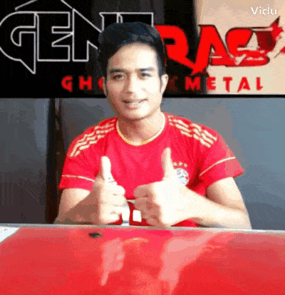 a man in a red shirt gives two thumbs up