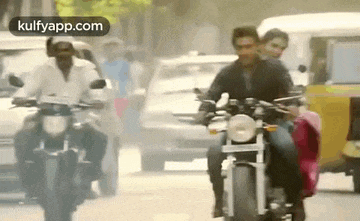 a group of people riding motorcycles down a busy street .