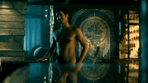 a shirtless man is standing in a bathtub with his reflection in the water