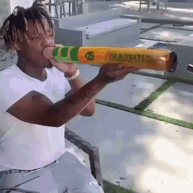 a man in a white shirt is holding a crayon that says graduation