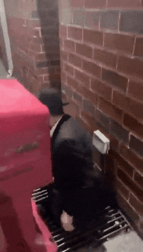 a man is kneeling down in front of a brick wall with a red box that says ' coca cola ' on it
