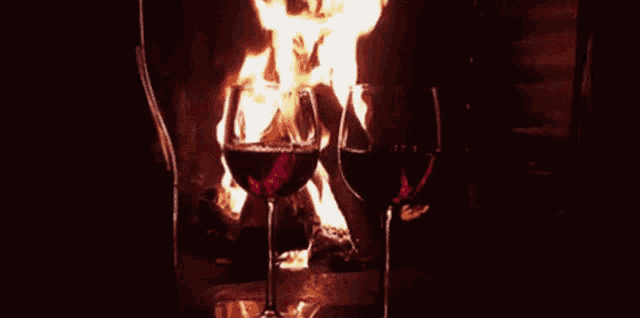 two glasses of wine in front of a fireplace