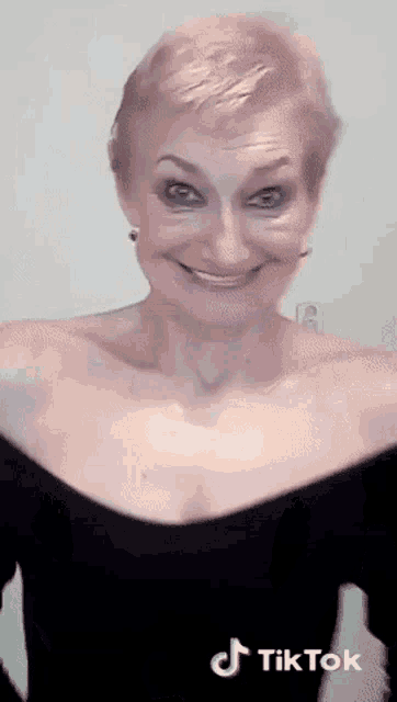 a woman with short hair is smiling and making a funny face .
