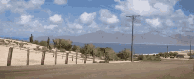 a fence along the side of a road with a mountain in the background