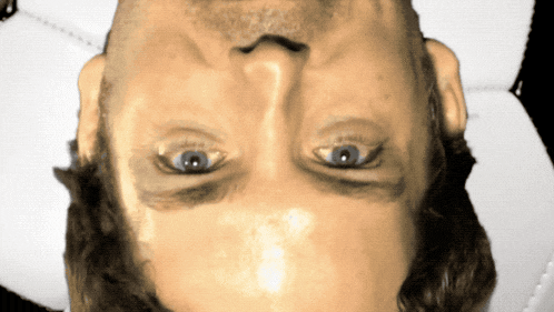 a close up of a man 's face with his eyes looking up