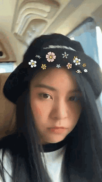 a girl wearing a black hat with pink and yellow flowers on it