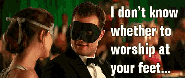 a man in a tuxedo and mask is talking to a woman in a white dress