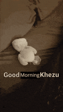 a teddy bear laying on a bed with the words good morning khezu