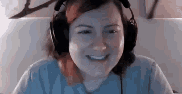 a woman wearing headphones is smiling while sitting in front of a computer .