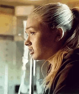 a close up of a woman 's face with a ponytail looking out of a window .