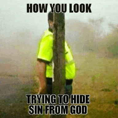 a man in a yellow shirt is standing next to a tree trunk .