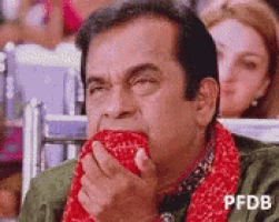 a man is eating a pomegranate while sitting in a chair in front of a crowd .