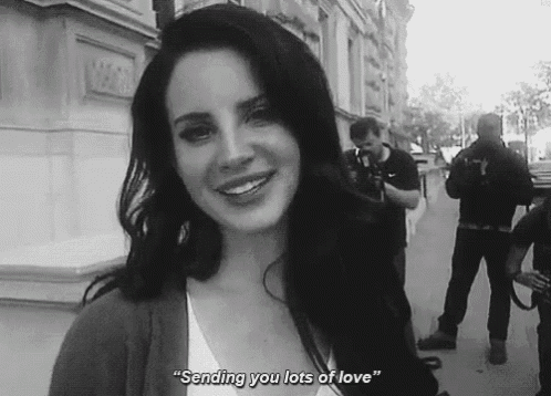a woman is smiling in a black and white photo with the words `` sending you lots of love '' written below her .