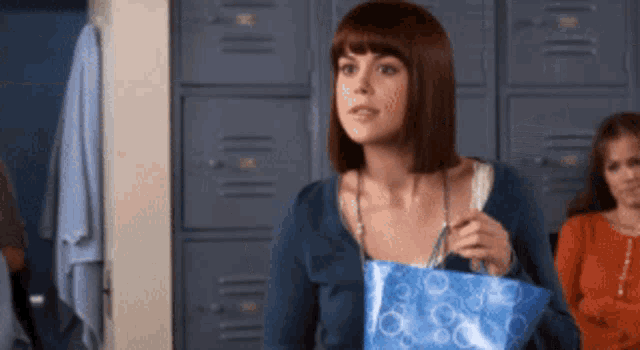a woman in a blue shirt is holding a blue bag
