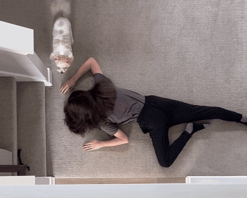 a woman crawls on the floor next to a dog