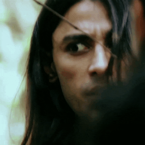 a close up of a man 's face with long hair looking at the camera .