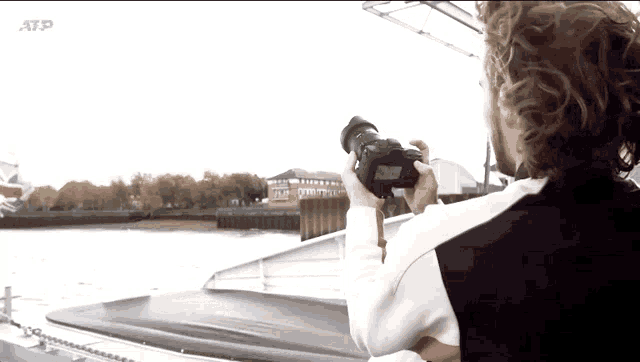 a man is taking a picture of a body of water with the atp logo behind him