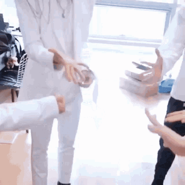 a man in a white suit is shaking hands with another man in a room .
