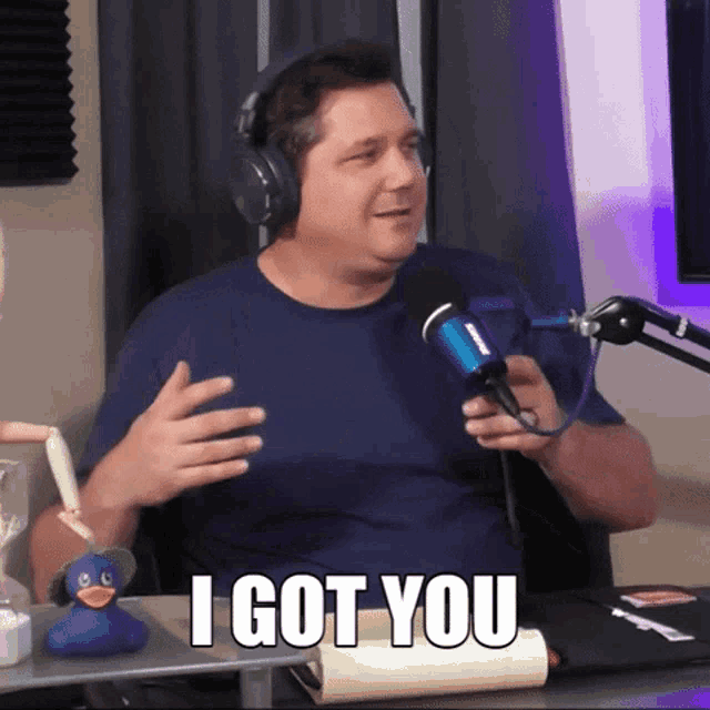 a man wearing headphones is holding a microphone and says i got you