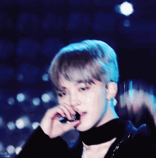 a close up of a person holding a microphone with 24/7 written on the bottom