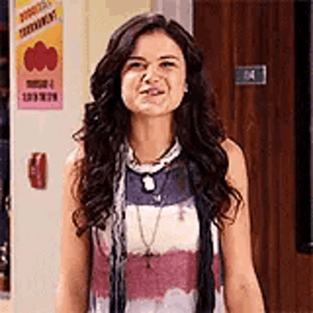 a woman is standing in front of a door wearing a tie dye shirt .