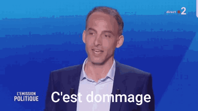 a man in a suit stands in front of a blue background that says " c'est dommage "