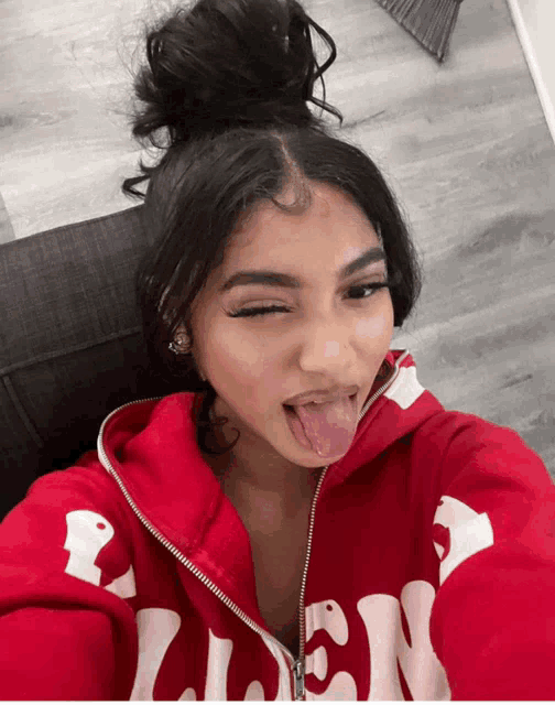 a woman wearing a red hoodie with the word glen on it sticking her tongue out