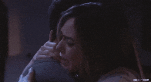 a man is hugging a woman in a dark room .