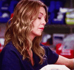 a woman in a blue scrub top is holding a baby in her lap .